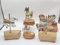 View showing six carousel horse figurines placed on a white surface, visible varying sizes and colorful paintwork