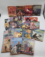 Photo showing the full lot of 25 sci-fi pulp magazines with colorful illustrated covers, laid out on a surface.