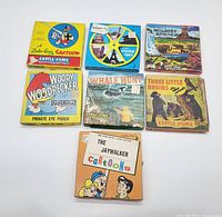 Photo showing all seven vintage 8mm film reels in original illustrated cardboard sleeves with colorful artwork and titles.