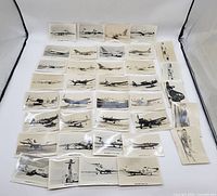 Top-down view showing 45 vintage real photo postcards of U.S. fighter and jet planes arranged flat with some overlapping. Black and white images.