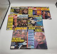 Nine Star Trek: The Next Generation magazines arranged in two rows, showing covers with various main characters and thematic art.
