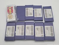 10 blue boxes of National Defense medals with one medal outside a box sealed in plastic showing the medal and ribbon detail.