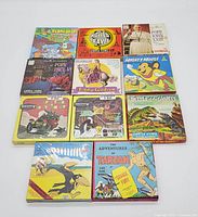 Lot of 11 vintage 8mm movie reels in original boxes shown from front, titles include Terry Bears, World Travel, The Story of Pope John XXIII, Pope Paul VI, Lady Godiva, Mighty Mouse, Speedy Delivery, Tweety, Battle of the Giants, The Ducktators, and The Adventures of Tarzan.
