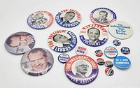Photo shows a collection of 21 vintage U.S. political campaign pinback buttons featuring various presidential candidates such as Nixon, Johnson, Humphrey, Muskie, and Anderson, with recognizable campaign slogans and portraits.
