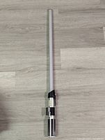 Full view of Anakin's lightsaber replica with illuminated white blade and detailed silver and black hilt.