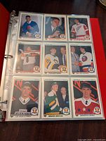 Page of hockey cards in a red binder with nine cards in view featuring players from various NHL teams in 1990-91 Upper Deck design.