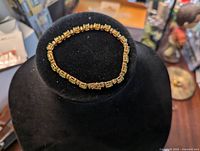 Side view of the 18K gold plated bracelet on black velvet stand, showing details of the rectangular links and clasp.