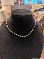 Front view of the pearl beaded necklace displayed on a black velvet bust showing pearl spacing and chain details.