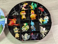 Top view of 17 Unova Pokémon figures arranged in black divider tray within the case showing all figures in separate compartments