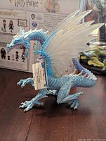 Front angle view of the Schleich Ice Dragon figure with visible blue body and white translucent wings, brand tag attached