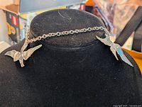 Silver tone necklace displayed on black mannequin, showing full chain with three seagull pendants.