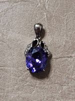 Front view of sterling silver pendant with deep purple oval amethyst gemstone faceted and set in decorative silver setting