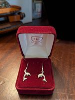 Photo of the sterling dolphin earrings displayed in open red velvet box.