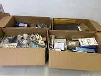 Four large cardboard boxes filled with assorted miscellaneous items, viewed from above.