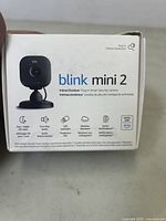 Front side of the Blink Mini 2 box showing camera image and key features: Day+Night HD View, Two-Way Audio, LED Spotlight, Weather Resistant, Smart Notifications, Alexa compatible.