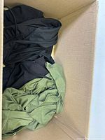 Box of clothing items including black and green garments