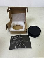 Black Fluance RW03 record weight stabilizer with user guide and open cardboard box showing foam insert for protection.