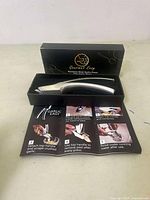 Garlic press set in black box with instruction leaflet visible.