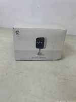 Front view of the boxed Jooan Smart Camera showing white packaging and a photo of the black camera on a stand.