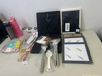 Photo of kitchen utensils, picture frames, and other items on a table.