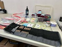 Overview of large craft and wool lot showcasing knitting needles, yarn skeins, ribbons, craft glue and small supplies on a table