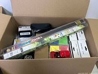 Box with fishing rod, toy vehicles, black glasses case, small boxes, and sticker sheets visible