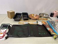 Full lot image showing pans, seed packets, heating pad, towels, and accessories arranged on floor
