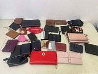 Overview of multiple wallets and coin purses on white table surface, showing varied colors, styles, and materials.