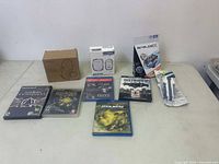 Full overview of the lot showing various video games, a boxed headset, USB adapters, and Beyblade set