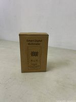 Closed cardboard box packaging with the text 'Smart Digital Multimeter' and illustration of the multimeter on front.