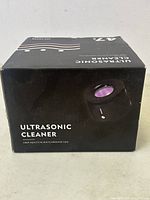 Photo of the original black box showing the label "ULTRASONIC CLEANER" with a control knob illuminated purple on the front face.