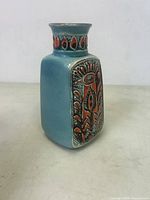 Front and side view of the square-shaped turquoise vase with orange decorative panels showing abstract floral and geometric designs.