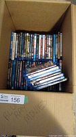 Top view of box containing multiple Blu-ray DVDs with spines facing up, showing assorted titles in standard cases