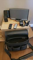 Full lot including BOSE Sounddock, two remotes, charger with power adapter, spare battery, and black travel case placed on a cardboard box and floor.