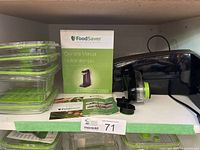 Photo of vacuum sealer machine with containers, owner's manual, and accessories on shelf.