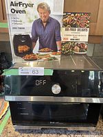 Front view of Instant Omni Plus air fryer oven with box showing features: air fry, rotisserie, dehydrate and two cookbooks included.