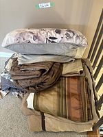 Full view of folded assorted bed linens including pillowcases and sheets in brown and beige tones, displayed on a chair.