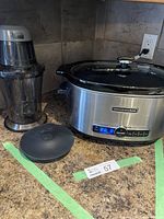 KitchenAid large slow cooker with stainless steel exterior, digital display and controls, glass lid, and black ceramic removable pot on granite countertop