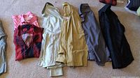 Lot displayed on carpet showing all six shirts, folded with visible colors including pink, red plaid, beige, mustard yellow, dark grey, black