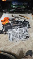 Full view of assorted hand tools including drill bit sets, socket sets, pipe wrench, wire brush, and measuring tape.