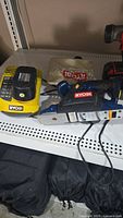 Ryobi cordless power planer with dust catcher and battery charger on shelf