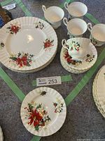 Overview of five dinner plates, five side plates, five cups and saucers laid out for inspection