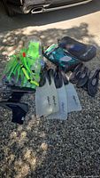 Full lot layout outdoors on ground showing fins, snorkels, masks, aqua boots, and complete snorkeling set in bag
