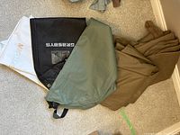 Multiple fabric suit storage bags in white, black labeled 'GRASSI', greenish-grey, and brownish fabric storage bags.