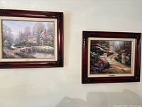 Photo showing both paintings hanging on a wall side by side, highlighting frames and art detail.