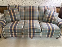 Front view of the three-seat sofa with plaid fabric and cushions arranged; shows overall condition and pattern.