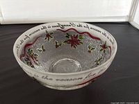 Crackle glass bowl with poinsettia decoration and cursive script around rim, photographed from above.