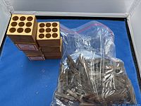 Wooden blocks with circular slots, stacked, adjacent to a sealed plastic bag with metal punches inside.
