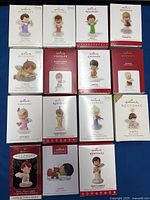15 boxed Hallmark Mary's Angels Christmas Ornaments arranged in three rows showing front of boxes with angel images and names.