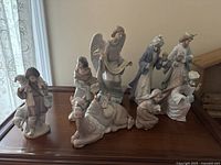 Group of Lladro porcelain nativity figurines displayed on wooden table